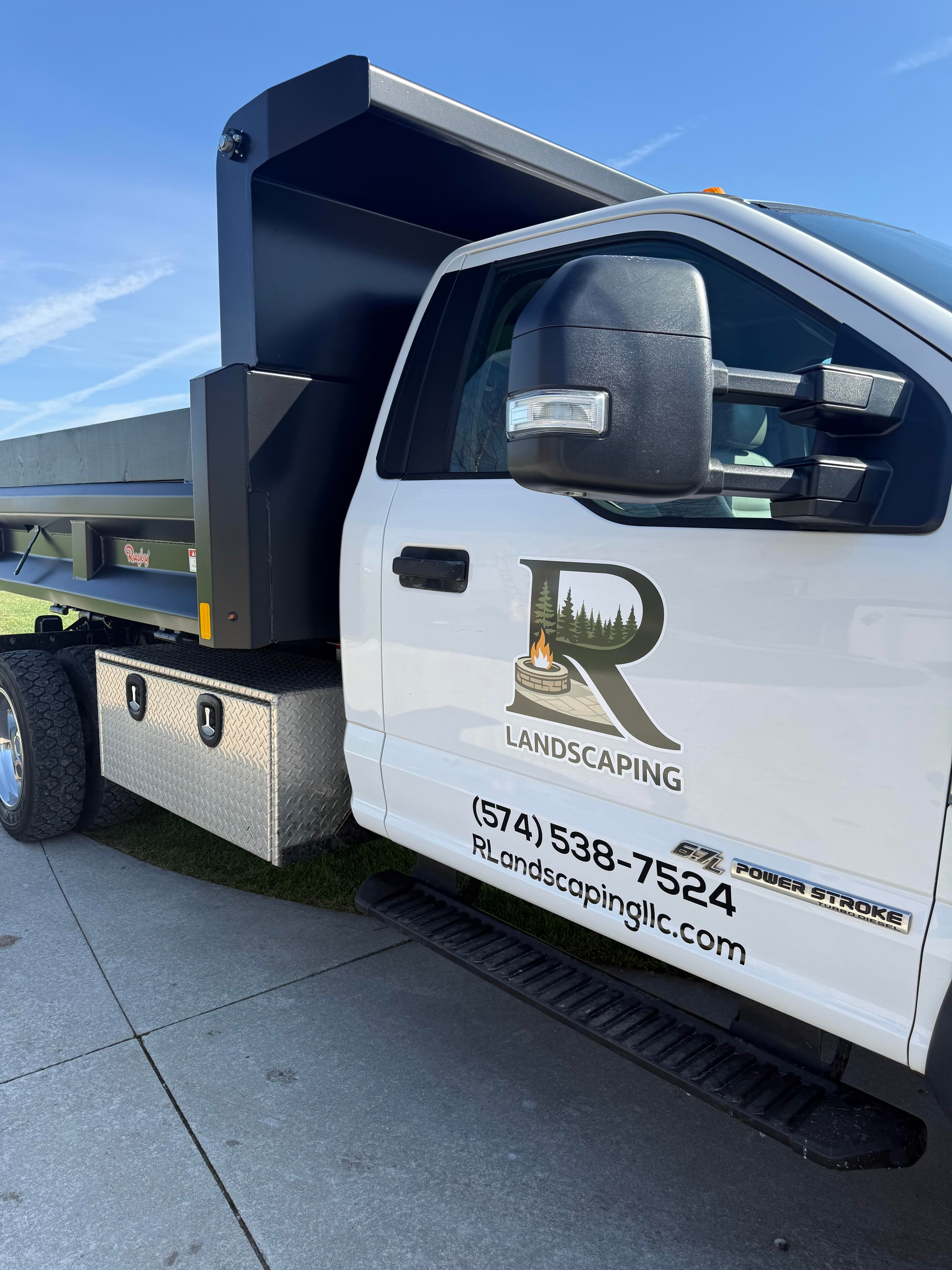 Landscaping truck with logo, phone number, and flatbed for hauling materials.