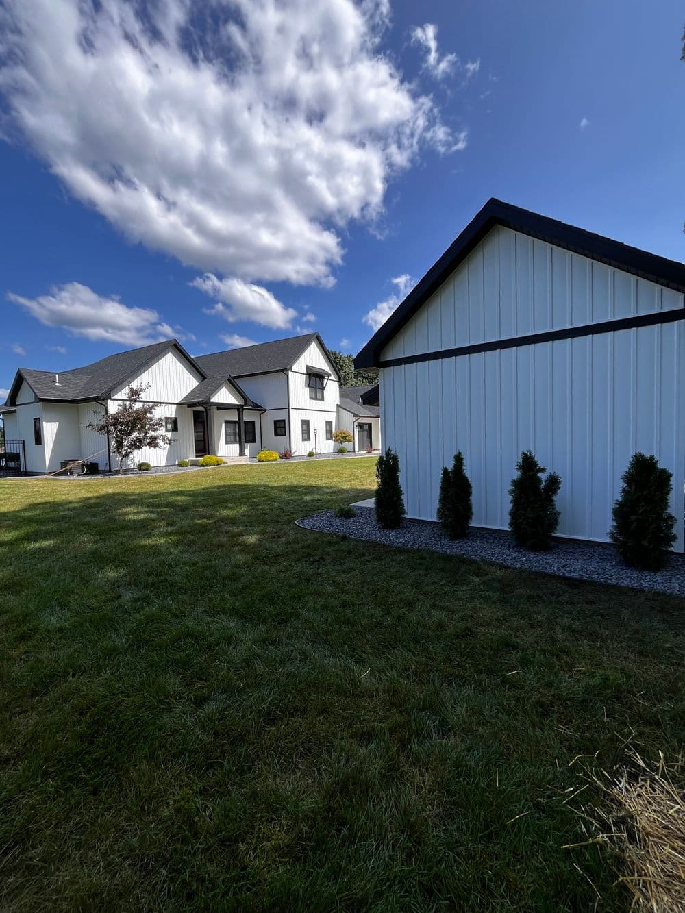 Modern suburban homes with white exteriors and black roofs under a blue sky.