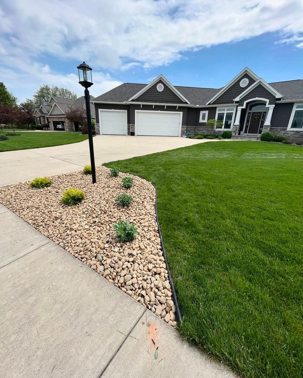Modern home with landscaped driveway featuring decorative stone and vibrant greenery.